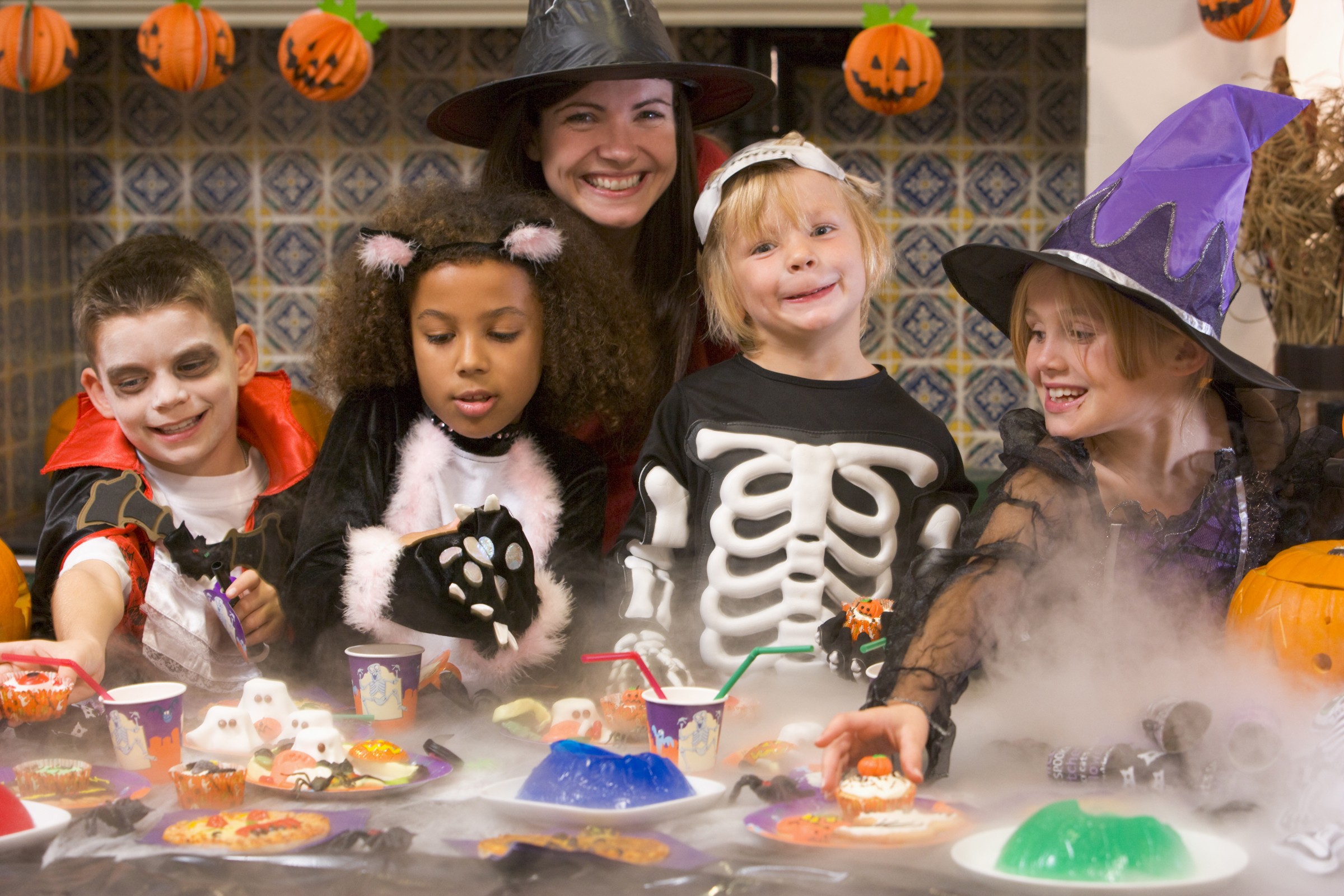 Four young friends and a woman at Halloween eating treats and sm